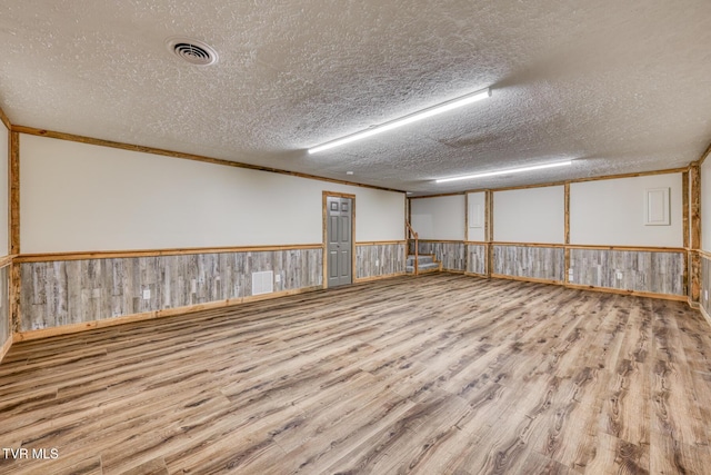 unfurnished room featuring crown molding, a textured ceiling, and light wood-type flooring