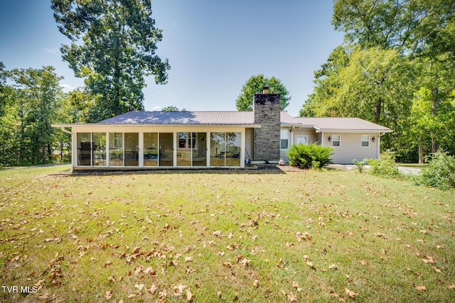 rear view of house with a sunroom and a lawn