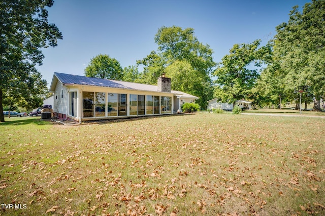 rear view of house featuring a yard and a sunroom