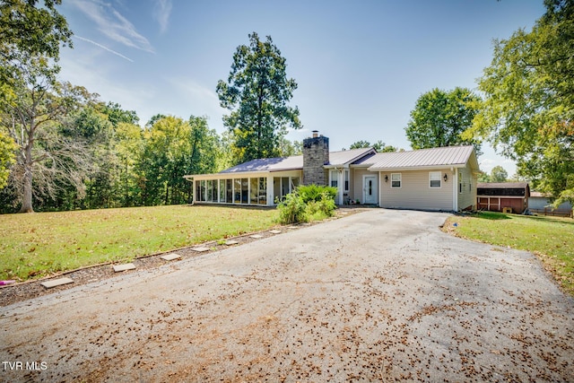 single story home featuring a front lawn and a sunroom