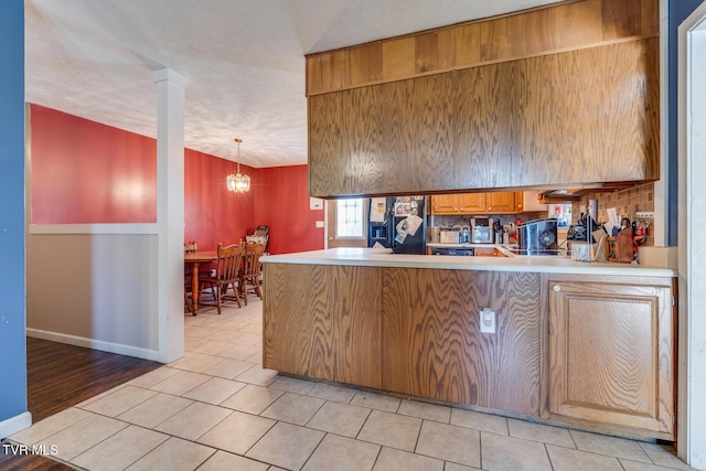 kitchen with decorative columns, hanging light fixtures, light tile patterned floors, kitchen peninsula, and a textured ceiling