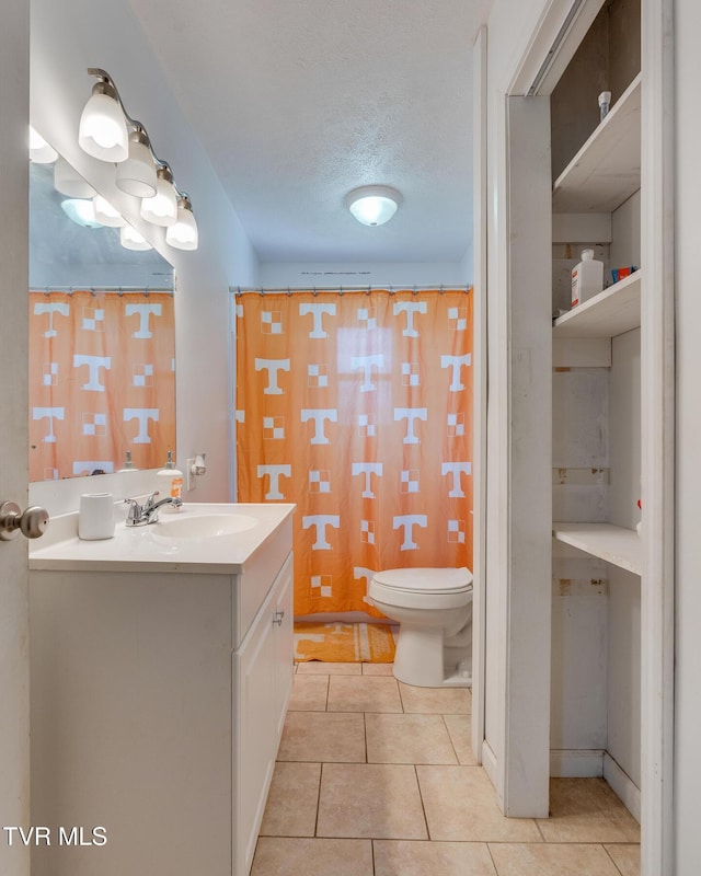 bathroom with tile patterned flooring, vanity, a textured ceiling, toilet, and walk in shower