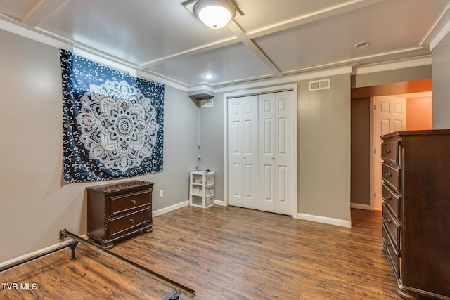 bedroom featuring coffered ceiling, dark wood-type flooring, crown molding, and a closet