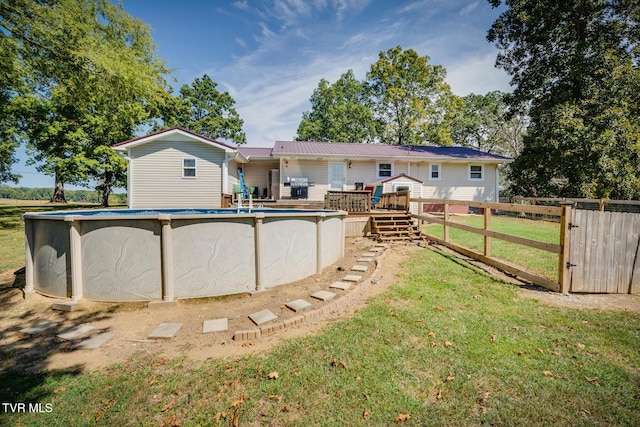 rear view of property featuring a pool side deck and a yard