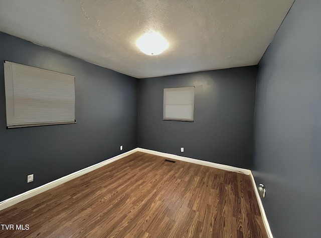 empty room with wood-type flooring and a textured ceiling