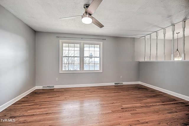 spare room featuring wood-type flooring, ceiling fan, and a textured ceiling