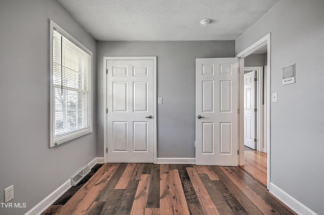 unfurnished bedroom featuring a textured ceiling and dark hardwood / wood-style flooring