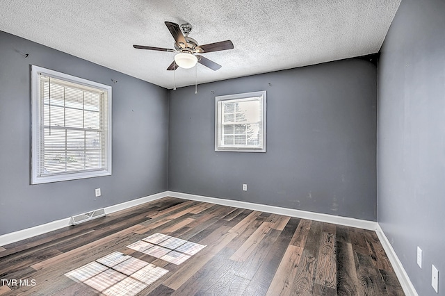 empty room with dark wood-type flooring, ceiling fan, and a textured ceiling