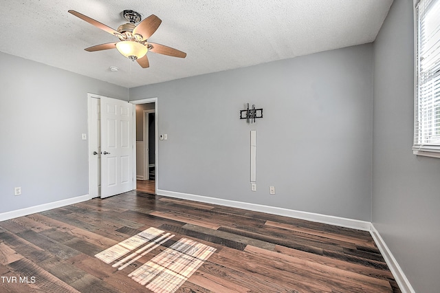 unfurnished room featuring ceiling fan, dark wood-type flooring, and a textured ceiling