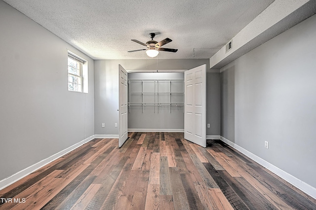 unfurnished bedroom featuring ceiling fan, dark hardwood / wood-style floors, a closet, and a textured ceiling