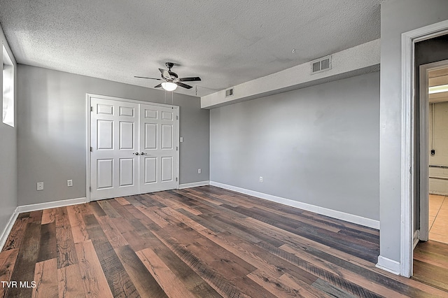 unfurnished bedroom with dark hardwood / wood-style flooring, ceiling fan, and a textured ceiling