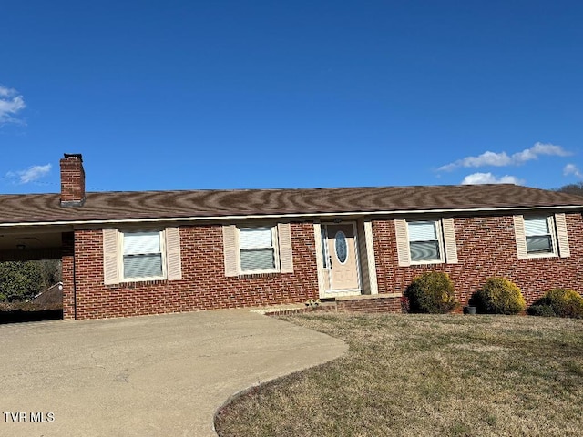 single story home featuring a chimney, a front lawn, and brick siding