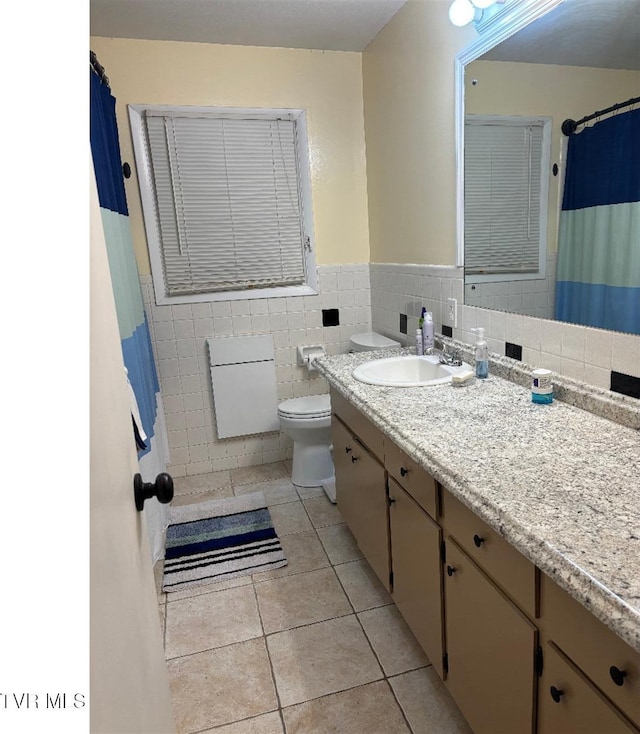 bathroom featuring vanity, toilet, tile patterned flooring, and tile walls