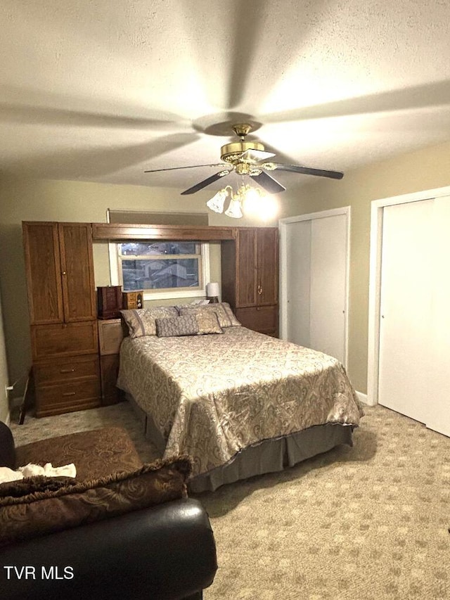 bedroom featuring multiple closets, ceiling fan, light colored carpet, and a textured ceiling