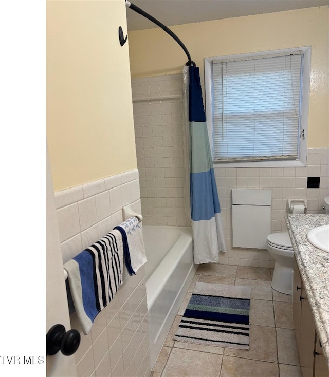 bathroom with toilet, a wainscoted wall, tile patterned floors, vanity, and tile walls