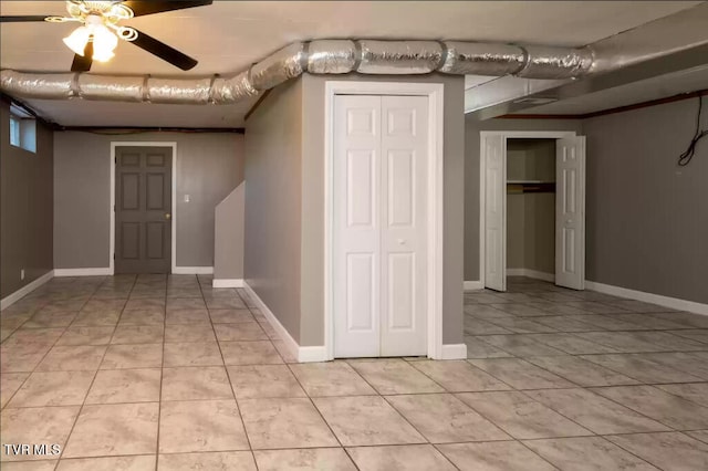 finished below grade area with light tile patterned floors, a ceiling fan, and baseboards