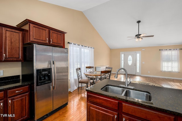 kitchen featuring sink, stainless steel fridge with ice dispenser, ceiling fan, dark stone counters, and light hardwood / wood-style floors