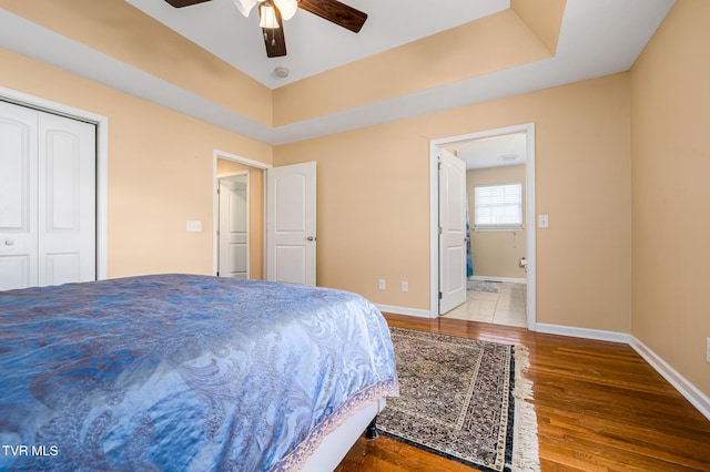 bedroom with hardwood / wood-style flooring, ceiling fan, a raised ceiling, and a closet