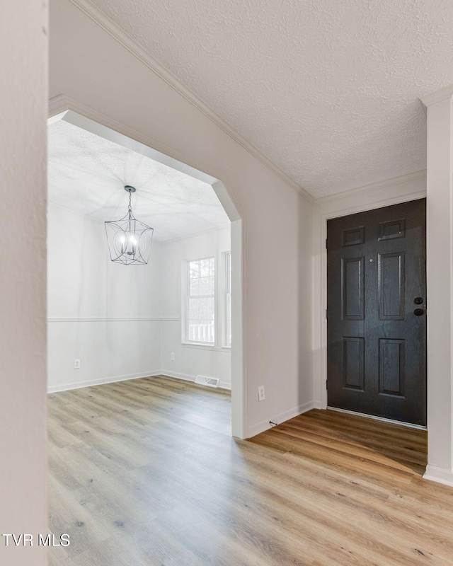 entryway with crown molding, a chandelier, light hardwood / wood-style flooring, and a textured ceiling