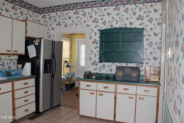 kitchen featuring light tile patterned floors, stainless steel fridge with ice dispenser, and white cabinets