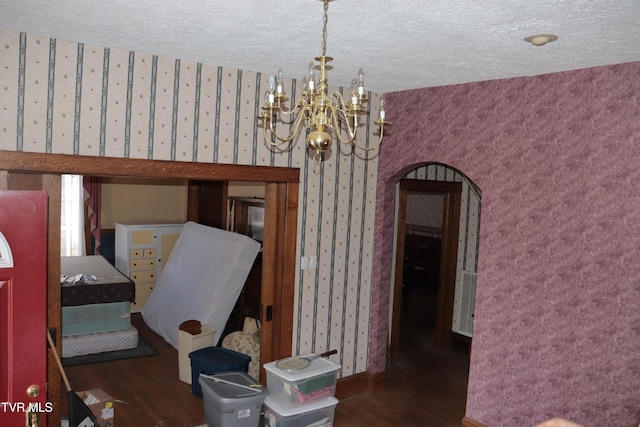 dining space featuring dark hardwood / wood-style flooring, a chandelier, and a textured ceiling