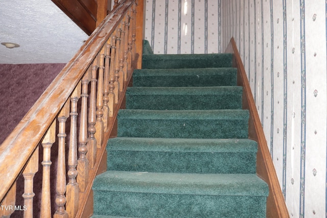 stairway featuring a textured ceiling