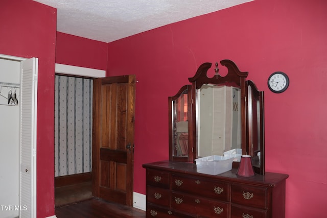 bedroom with dark hardwood / wood-style floors and a textured ceiling