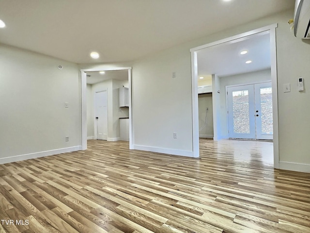 spare room with french doors, a wall mounted air conditioner, and light hardwood / wood-style floors