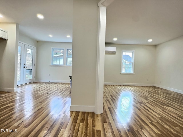 unfurnished living room featuring french doors, hardwood / wood-style floors, and an AC wall unit