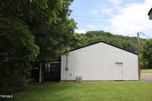 view of outdoor structure with central AC and a lawn