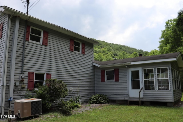 view of property exterior with central AC and a lawn