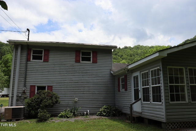 view of side of home with a yard and central air condition unit