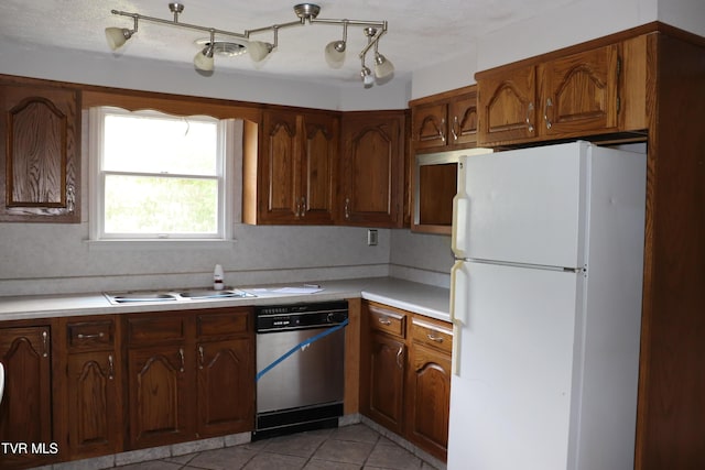 kitchen featuring white refrigerator, stainless steel dishwasher, sink, and light tile patterned floors