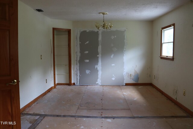 unfurnished room featuring a chandelier and a textured ceiling