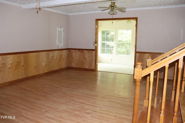 empty room featuring a textured ceiling, light hardwood / wood-style flooring, ornamental molding, and ceiling fan