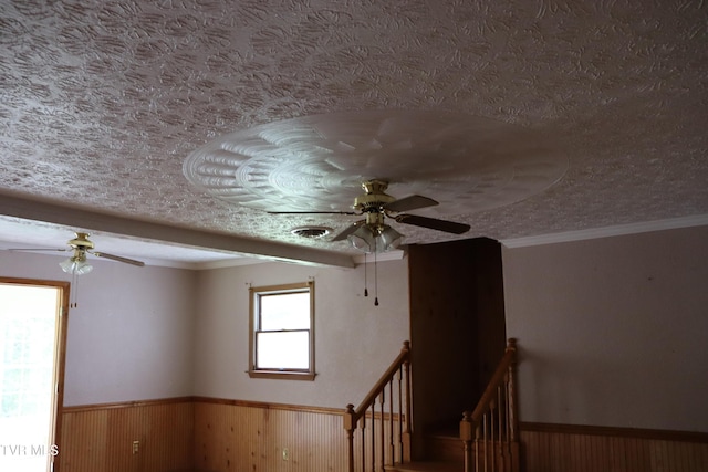 interior space featuring ceiling fan, a textured ceiling, and wood walls