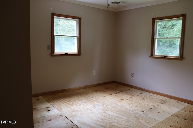 empty room with crown molding and a healthy amount of sunlight