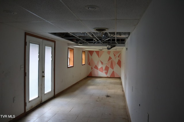 basement featuring a paneled ceiling and french doors