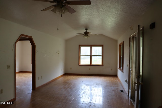 spare room with vaulted ceiling, ceiling fan, a textured ceiling, and light hardwood / wood-style floors