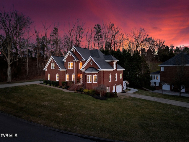 traditional-style home featuring driveway, a front lawn, an attached garage, and brick siding