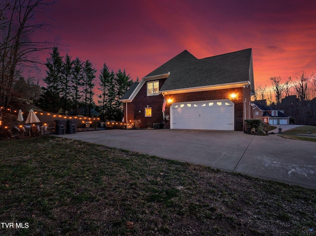 traditional home featuring a front yard, brick siding, driveway, and an attached garage