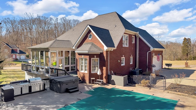 exterior space with a patio, brick siding, fence, a fenced in pool, and a hot tub