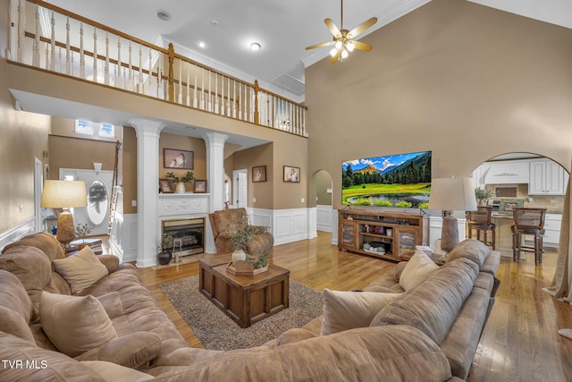 living room featuring ceiling fan, wood finished floors, wainscoting, and a fireplace with flush hearth