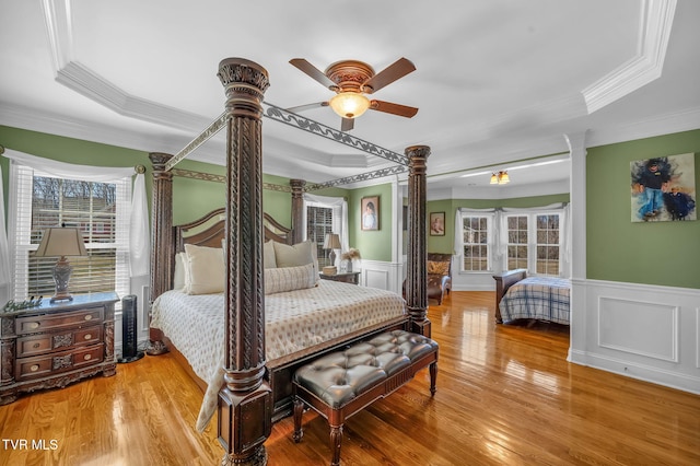 bedroom featuring crown molding, wood finished floors, and wainscoting