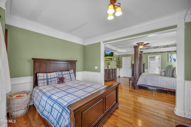 bedroom with a wainscoted wall, crown molding, and light wood-style flooring