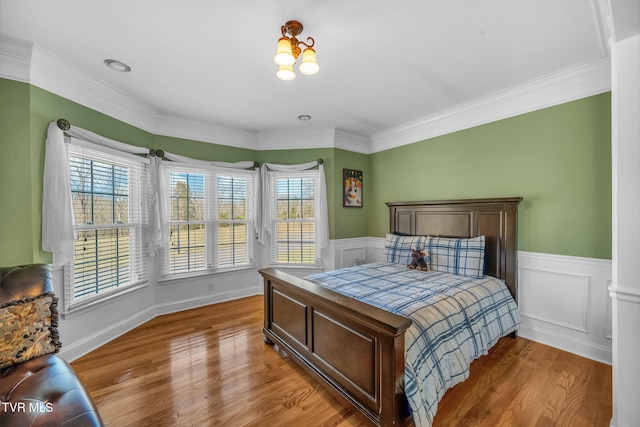 bedroom featuring access to exterior, crown molding, a wainscoted wall, and light wood-style floors