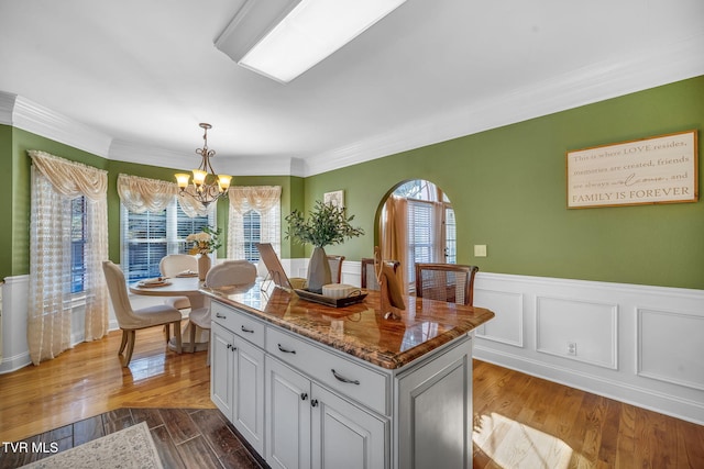 kitchen with a kitchen island, dark stone countertops, dark wood-type flooring, decorative light fixtures, and a chandelier