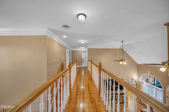 hallway featuring crown molding, lofted ceiling, visible vents, light wood-style flooring, and an upstairs landing