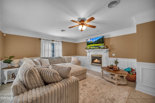 living room featuring light tile patterned floors, a lit fireplace, visible vents, and ornamental molding