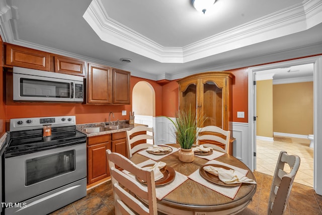 kitchen with a raised ceiling, visible vents, appliances with stainless steel finishes, wainscoting, and a sink